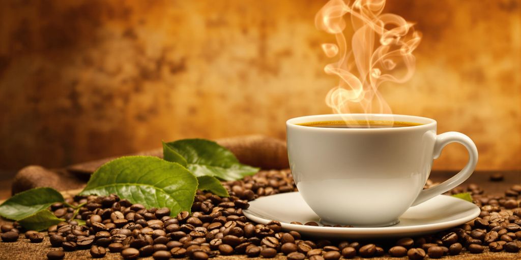 A cup of Brazilian coffee with coffee beans and leaves.