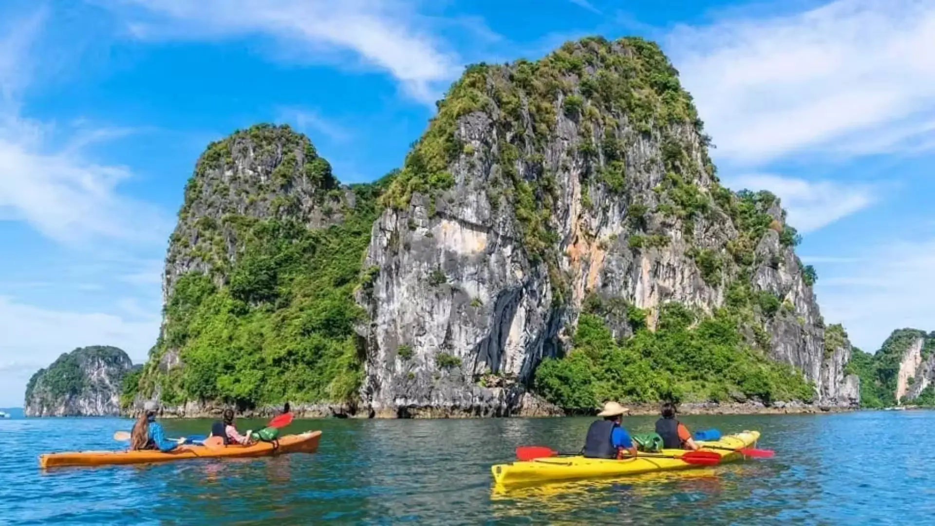 Travelers kayaking among limestone islands in Ha Long Bay Vietnam