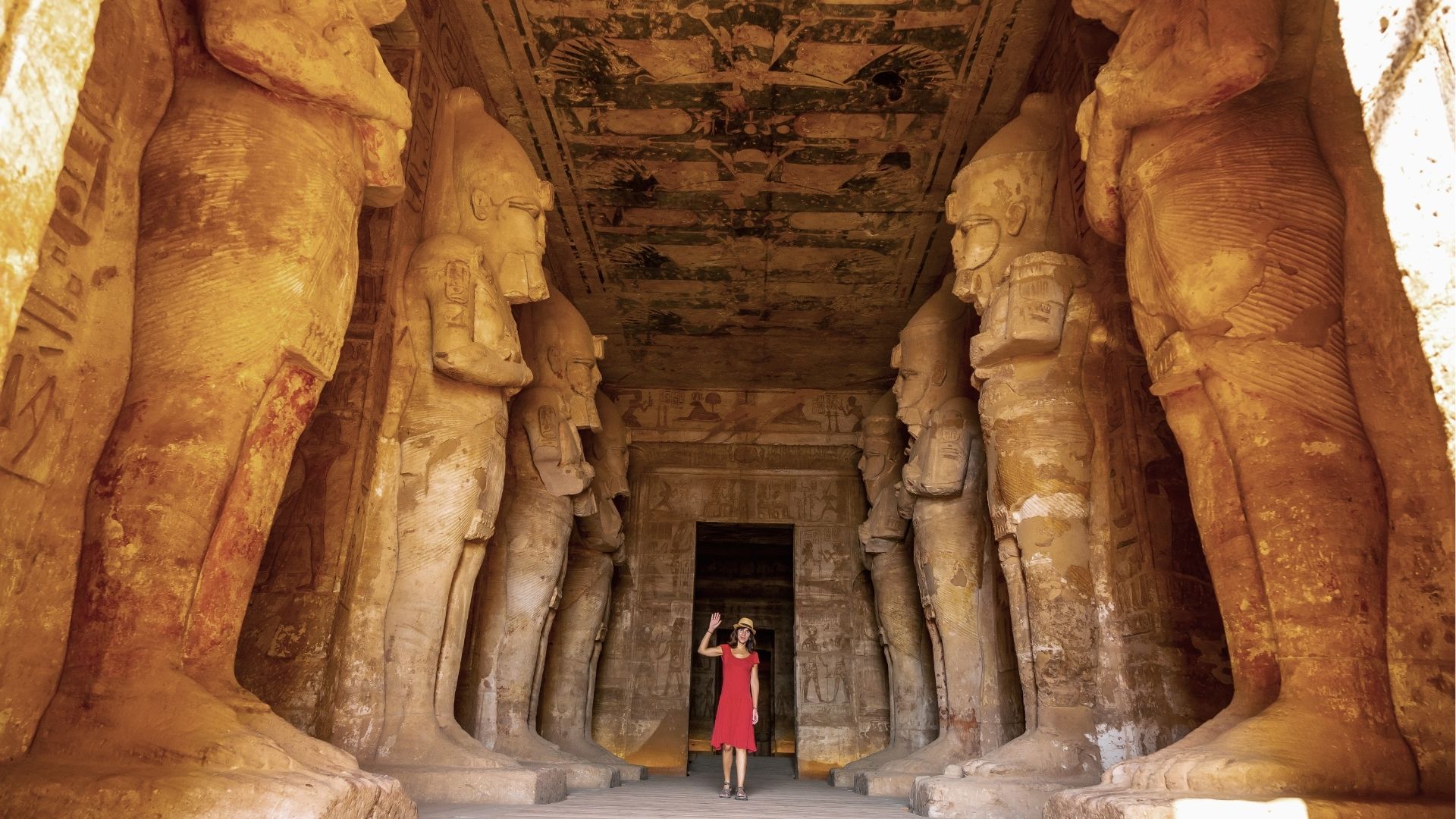 Visitor inside ancient Egyptian temple with large statues.