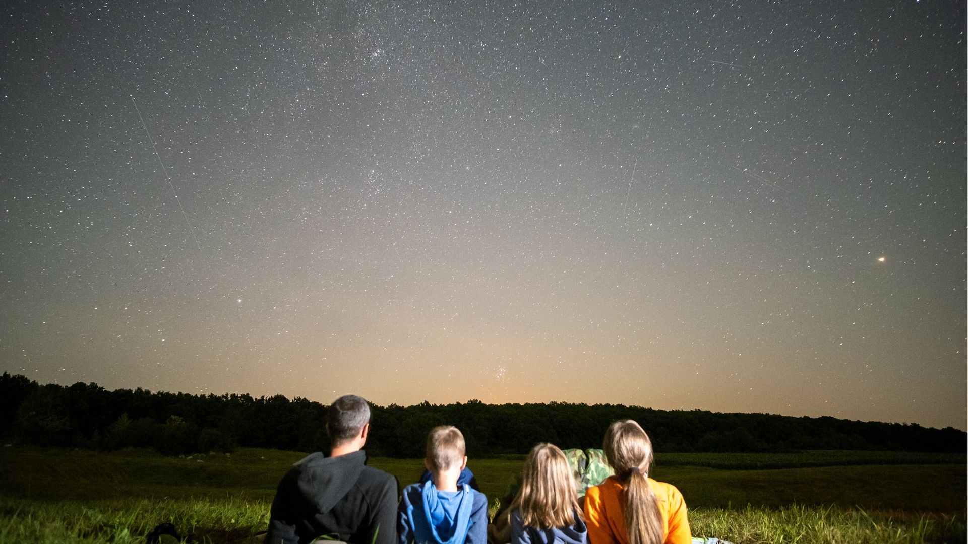 Family stargazing under a clear night sky