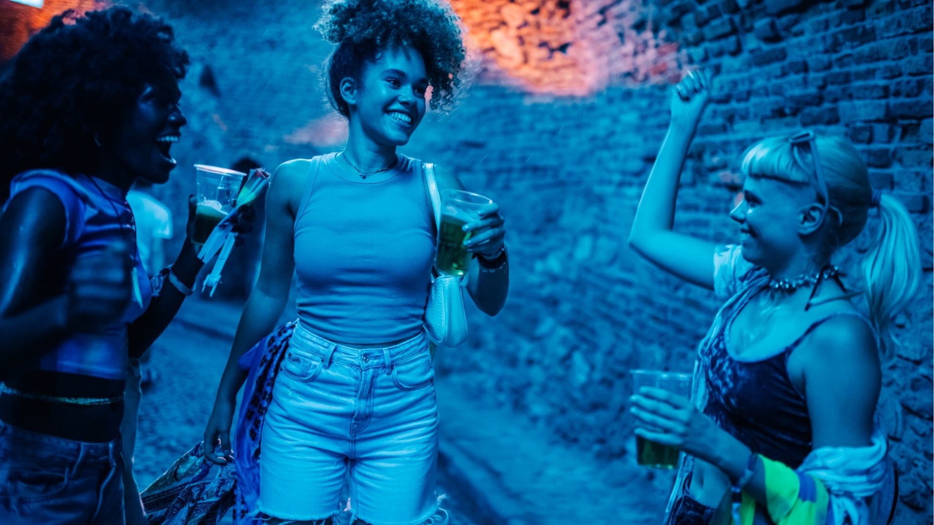 Young women drinking and having fun at night outdoor party