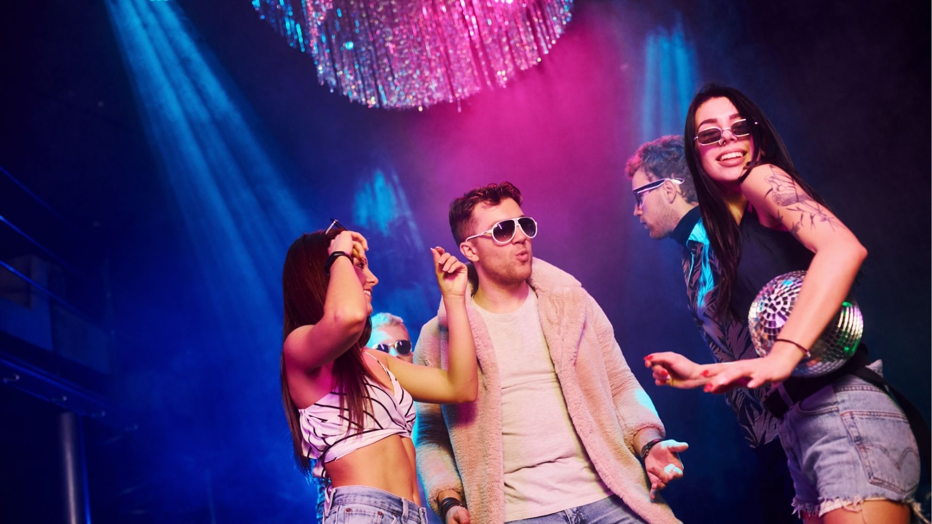 Young people is having fun in night club with colorful laser lights