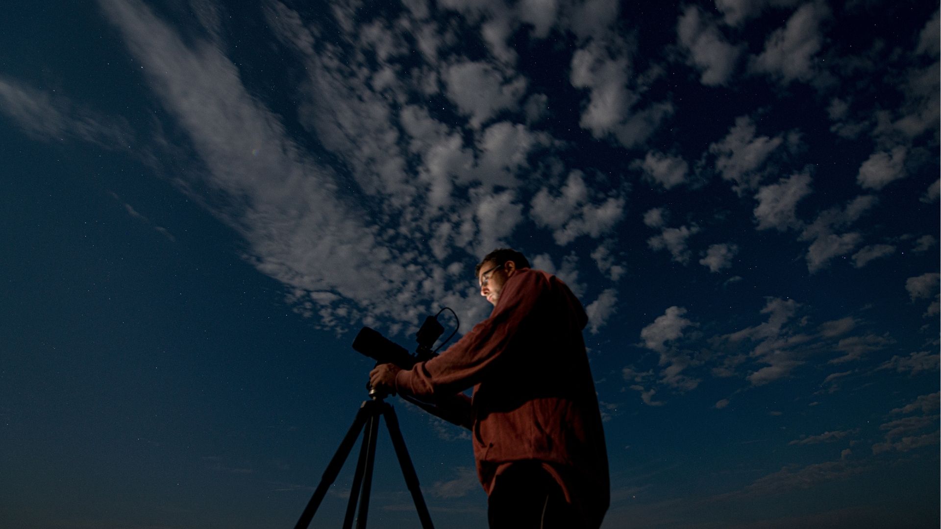 Man shooting the night starry sky with a tripod
