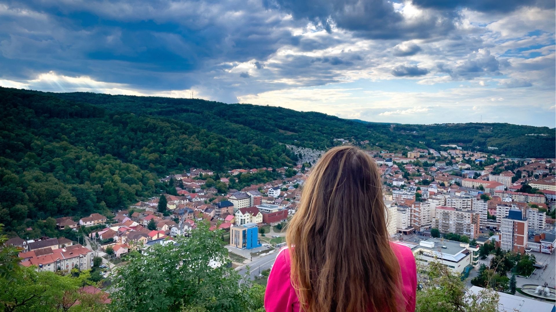 Young woman with long brown hair looking at the city from the top