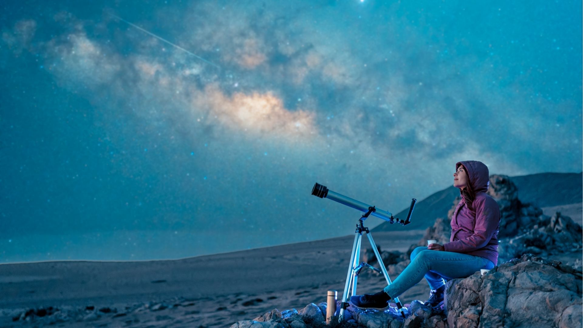 Woman sitting in the desert alone contemplating the starry sky and the milky way in the background