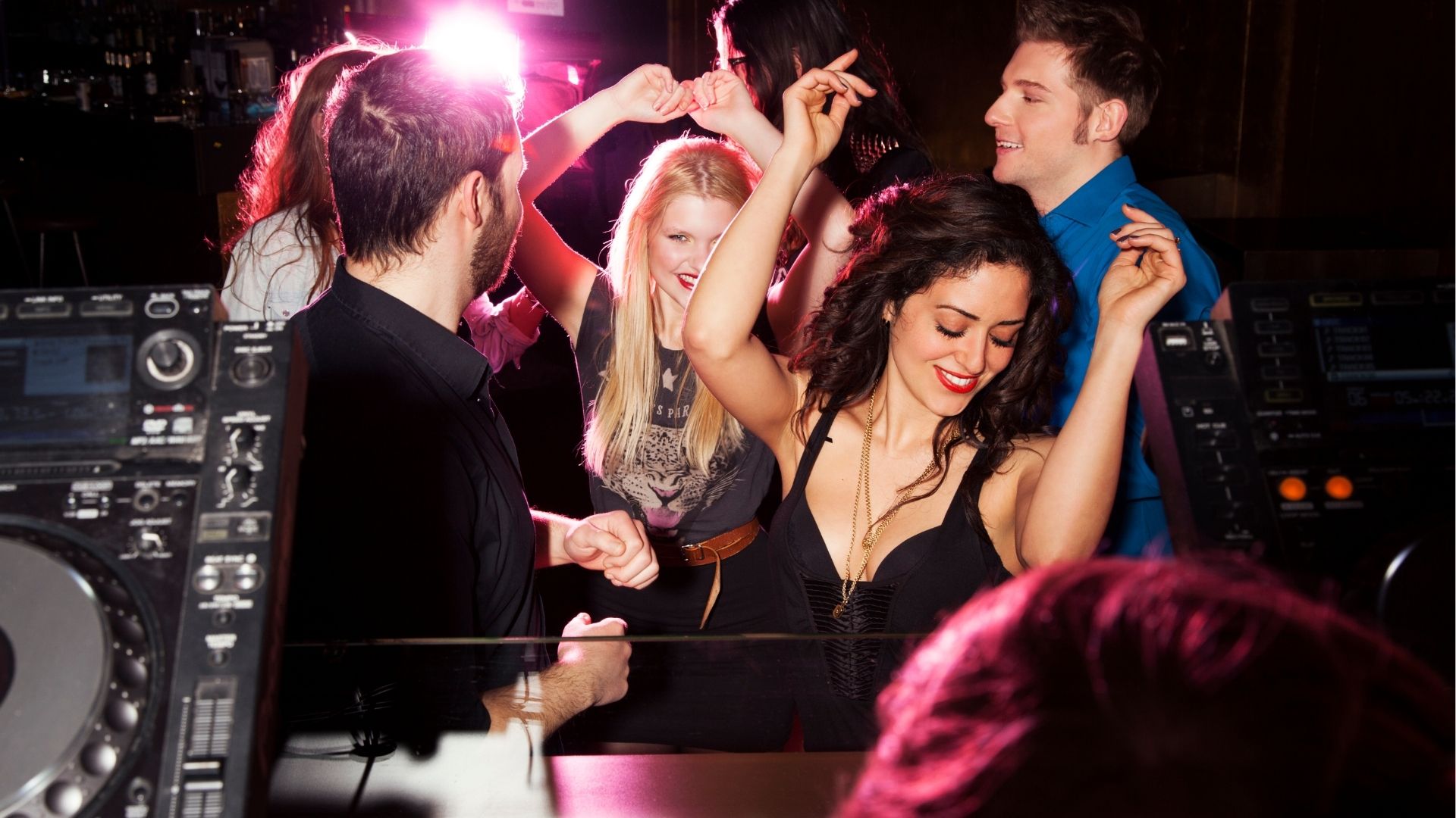 Group of friends dancing in front of DJ in nightclub