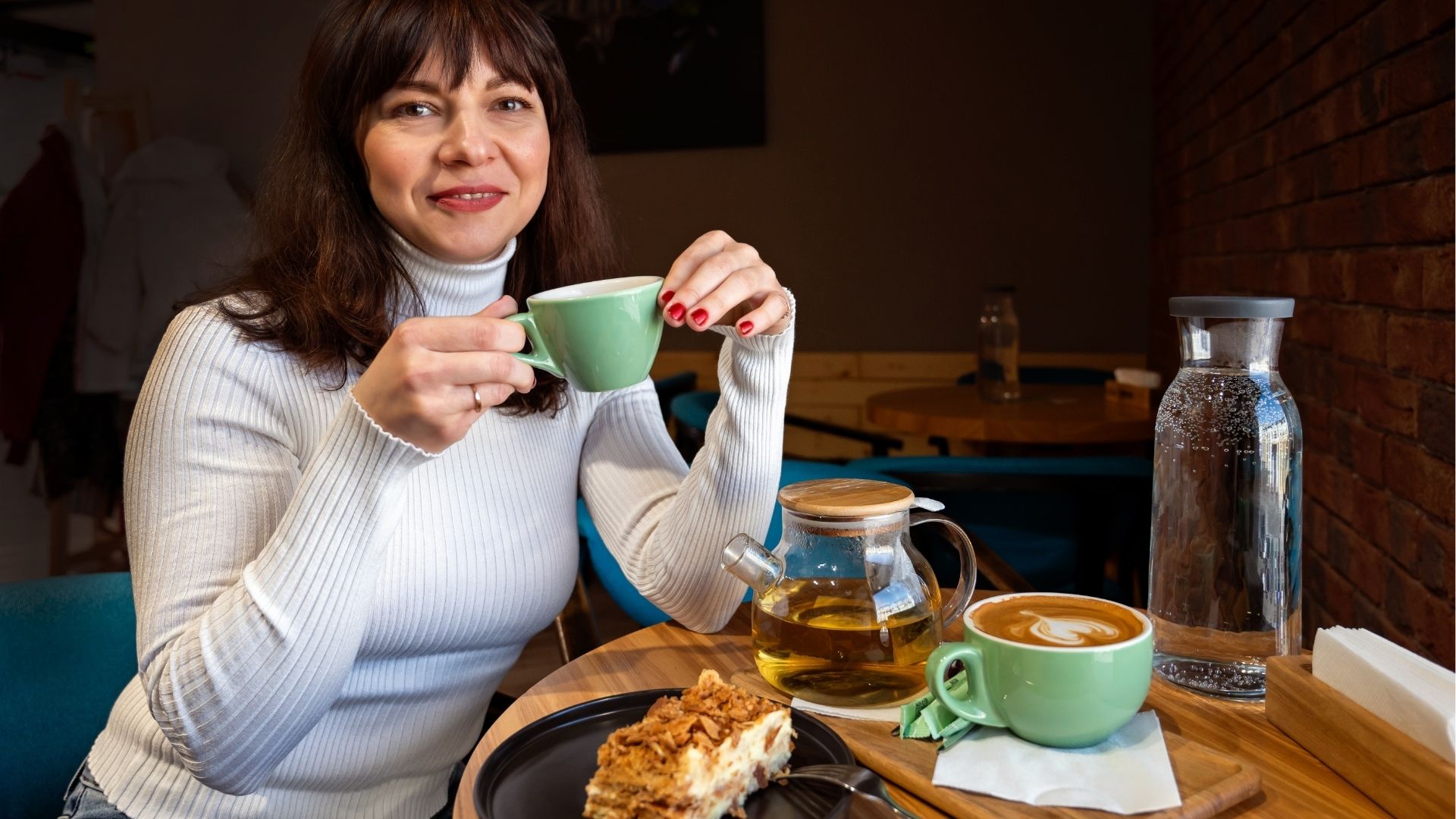 Mature woman with cup of hot tea and cake in cafe