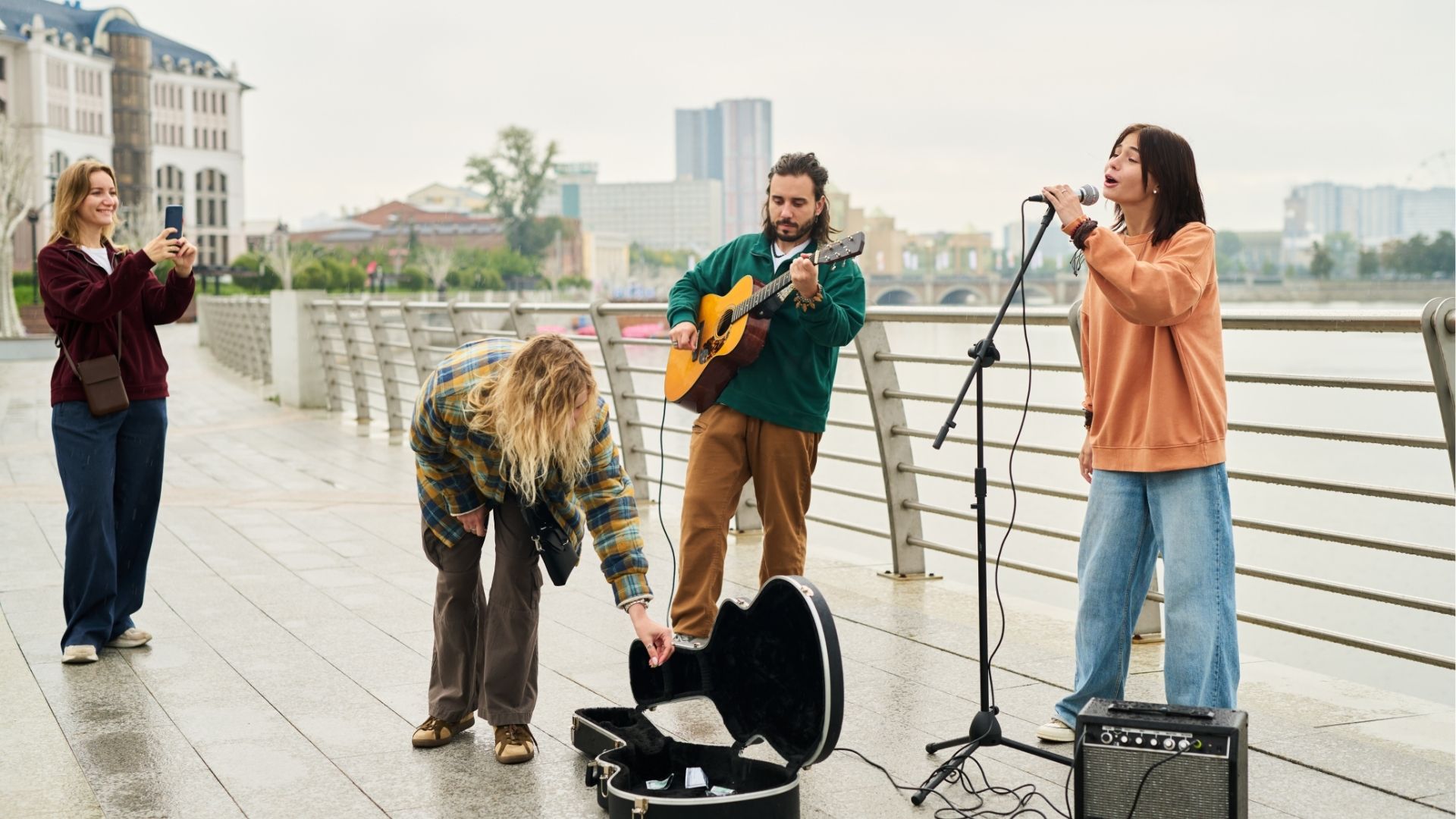 Young Caucasian Woman Singing While Young Man Playing Guitar Outdoors