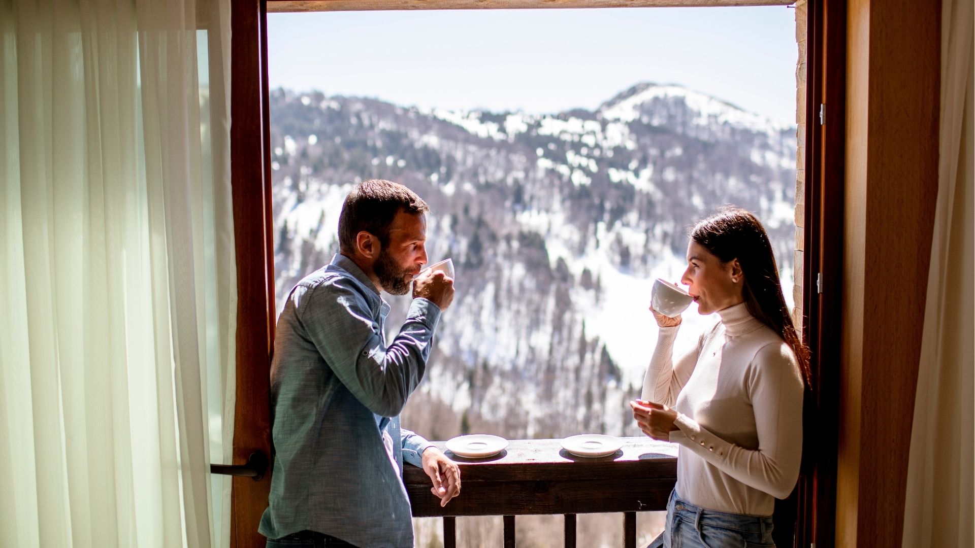 Young couple with cups of hot tea at winter window
