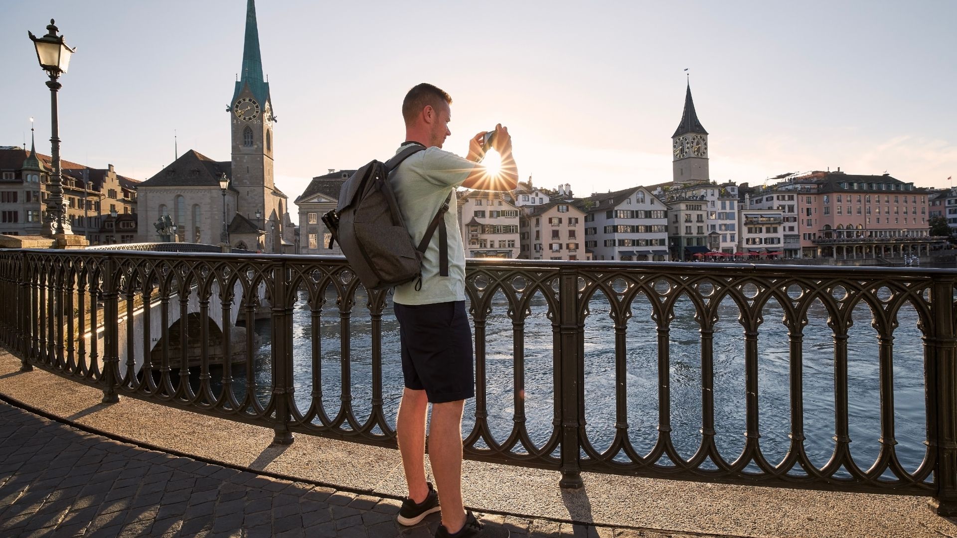 Man photographing cityscape of old town at beautiful sunset. Zurich, Switzerland.
