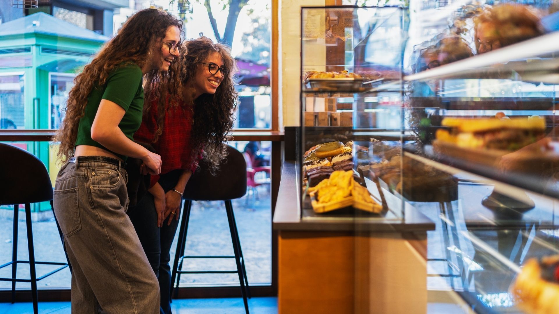 Friends choosing pastries in a modern cafe, Switzerland
