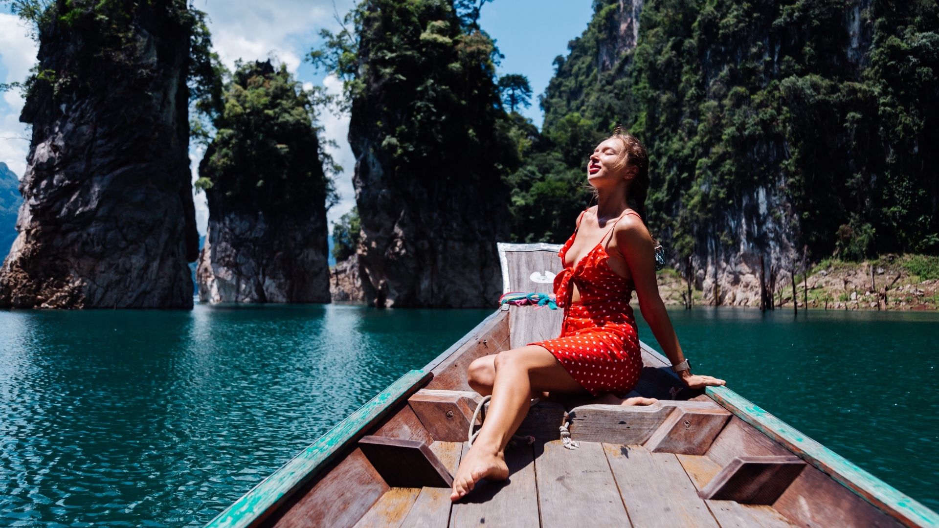 Woman tourist in red summer dress on thai asian boat on vacation
