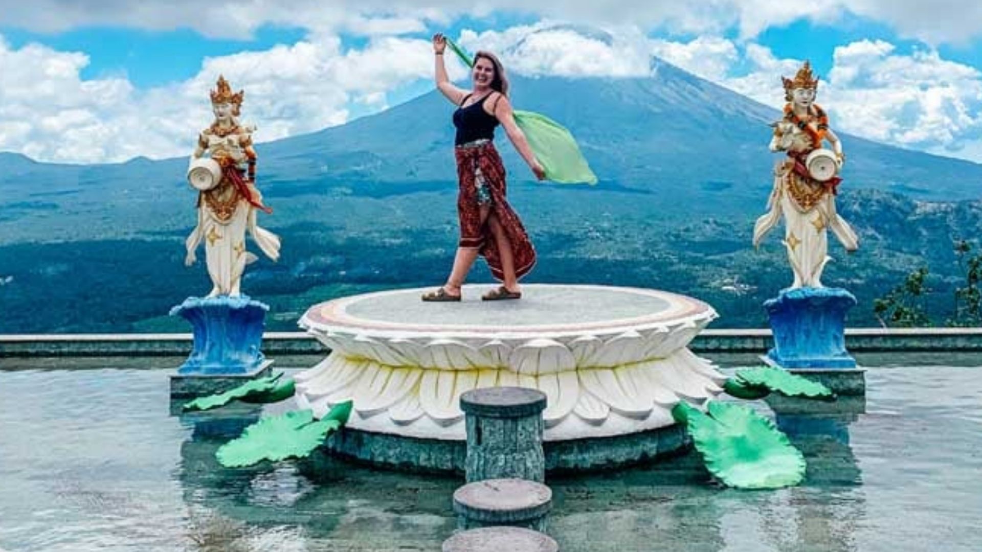 Traveler at a scenic Indonesia viewpoint with statues and mountains.