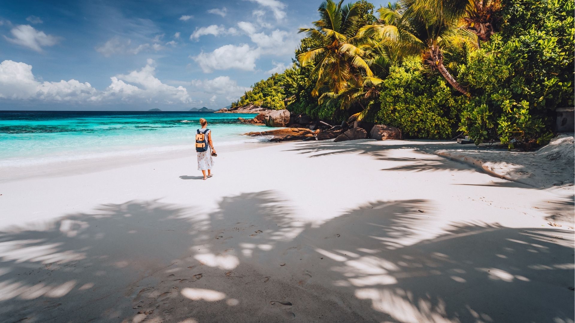 Female tourist enjoy summer vacation on tropical island. Sand beach, with shadows of palm trees 