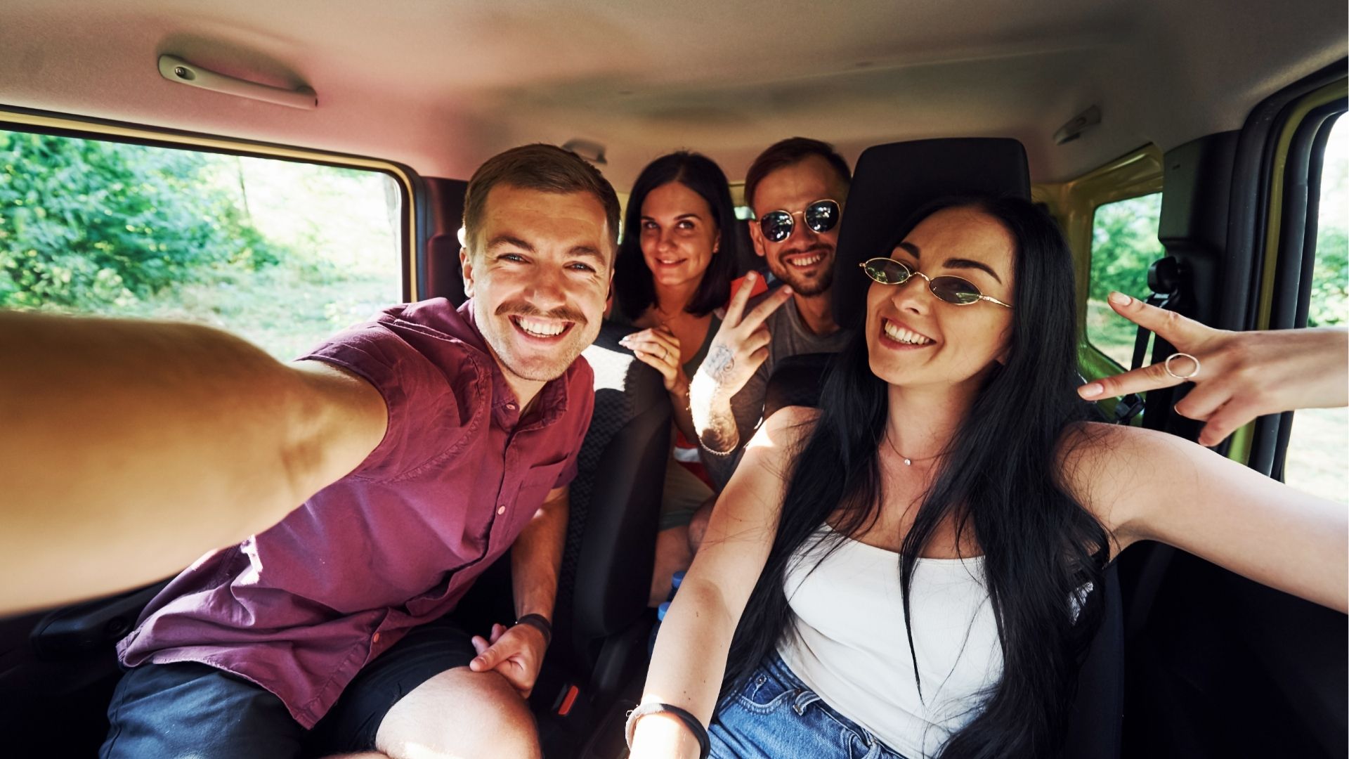 Young and cheerful people making a selfie inside a car enjoying weekend