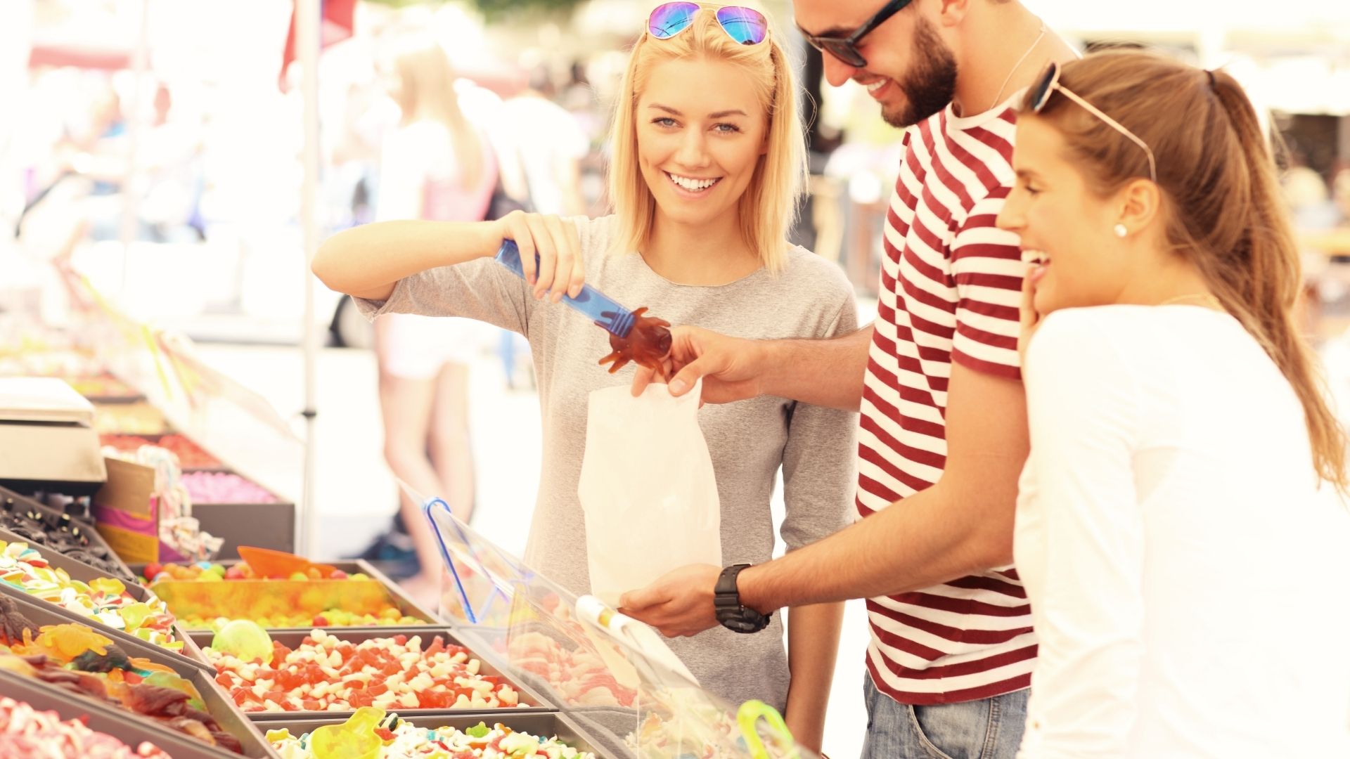 Group of friends buying jelly sweets on market
