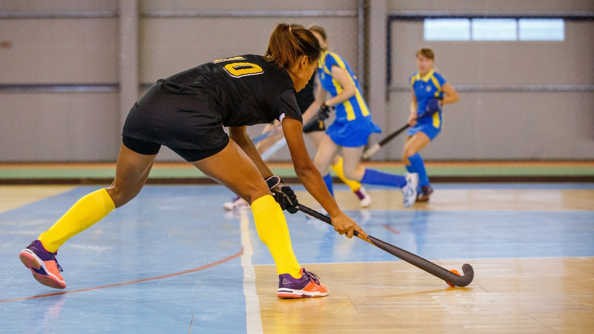 Young woman hockey player playing indoor hockey
