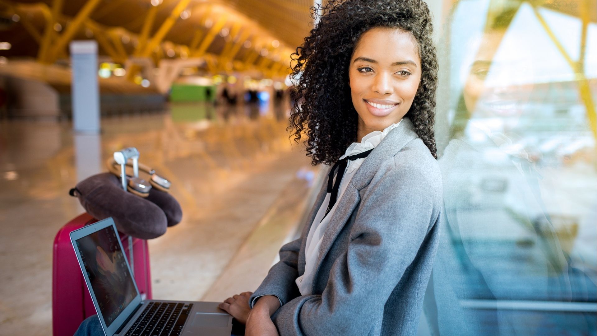 Woman working with laptop at the airport waiting at the window
