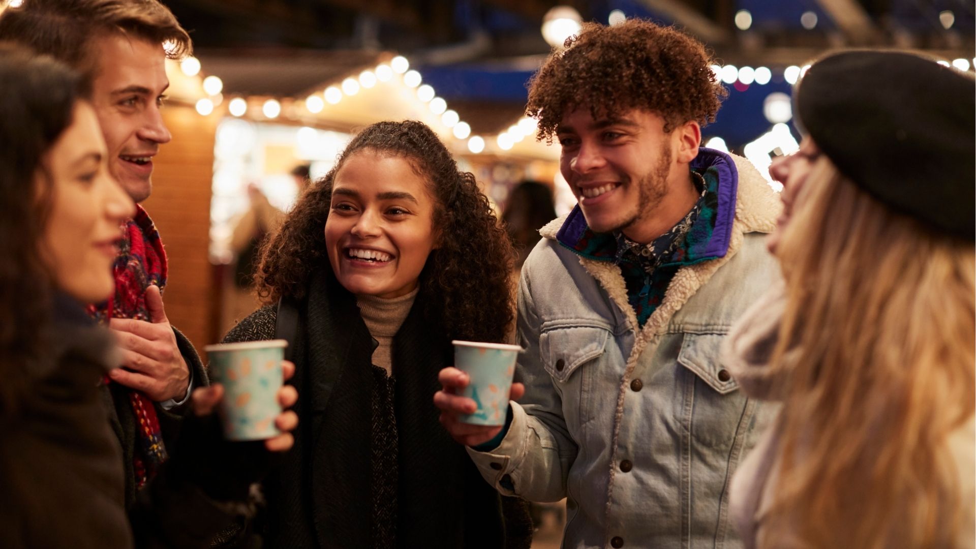 Group Of Friends Drinking Mulled Wine At Christmas Market
