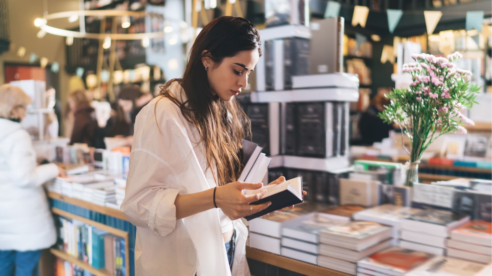 Woman reading a book at FIL Guadalajara while choosing literature to purchase