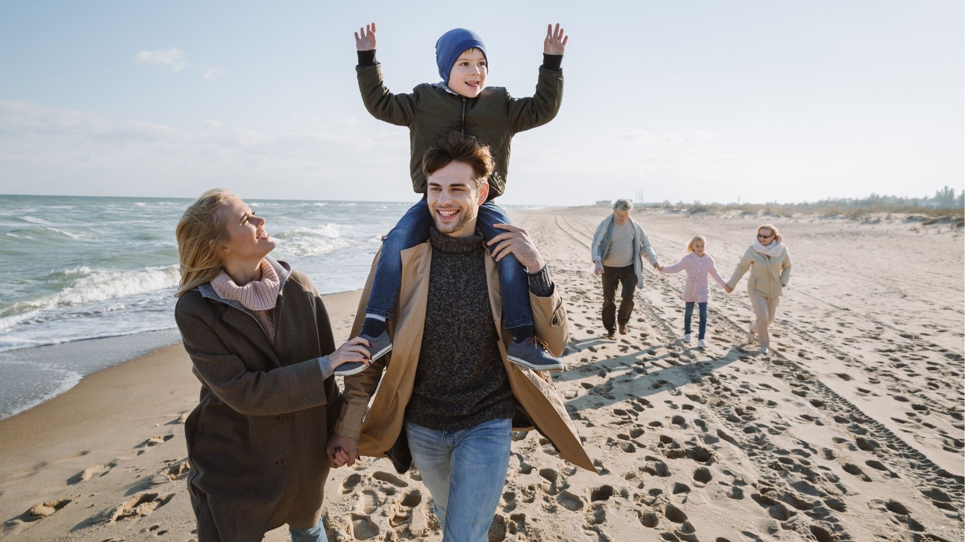 Happy multigenerational family walking together on seashore
