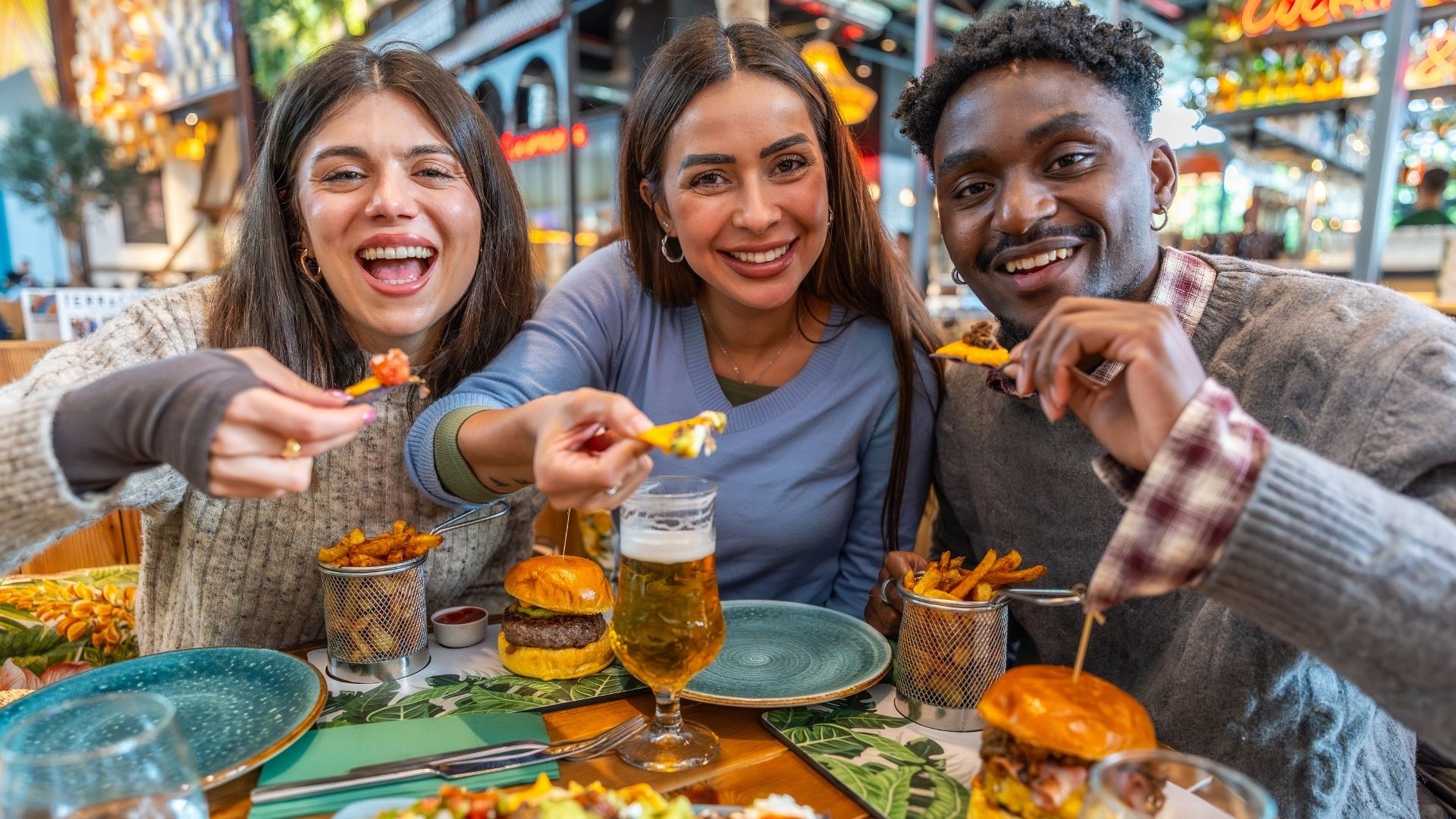 Friends eating nachos, burgers and fries at restaurant