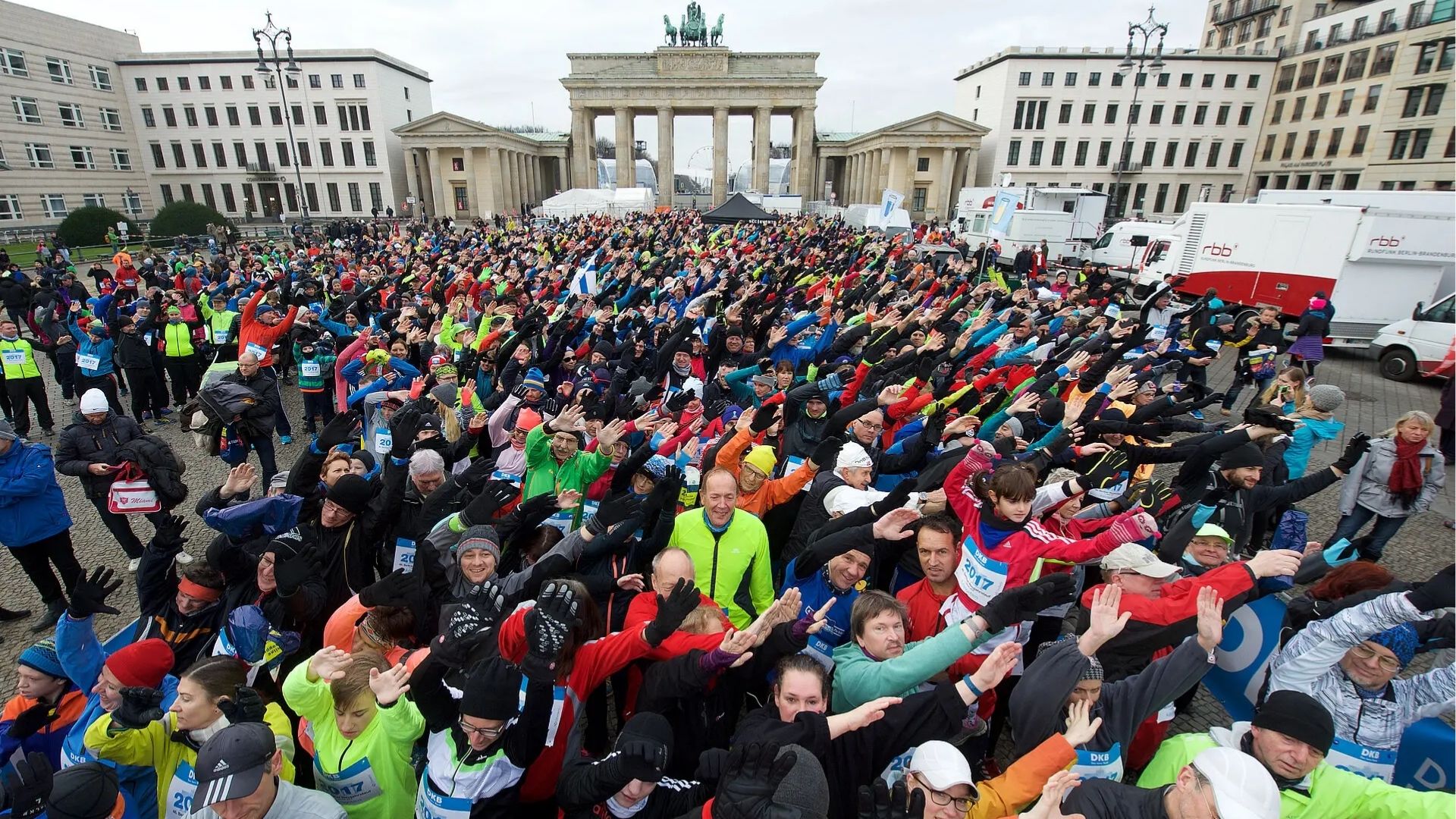 Large crowd of runners warming up in front of the Brandenburg Gate during a Berlin event.