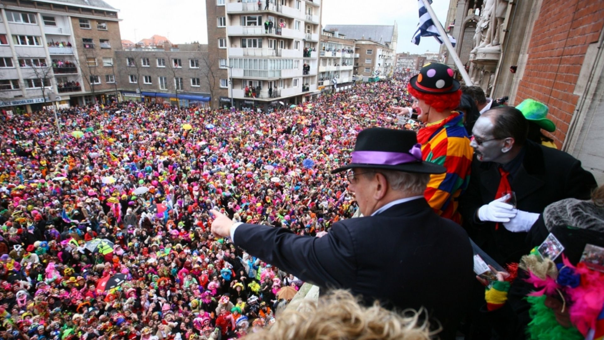 Participants in bright costumes and umbrellas at Dunkirk Carnival parade