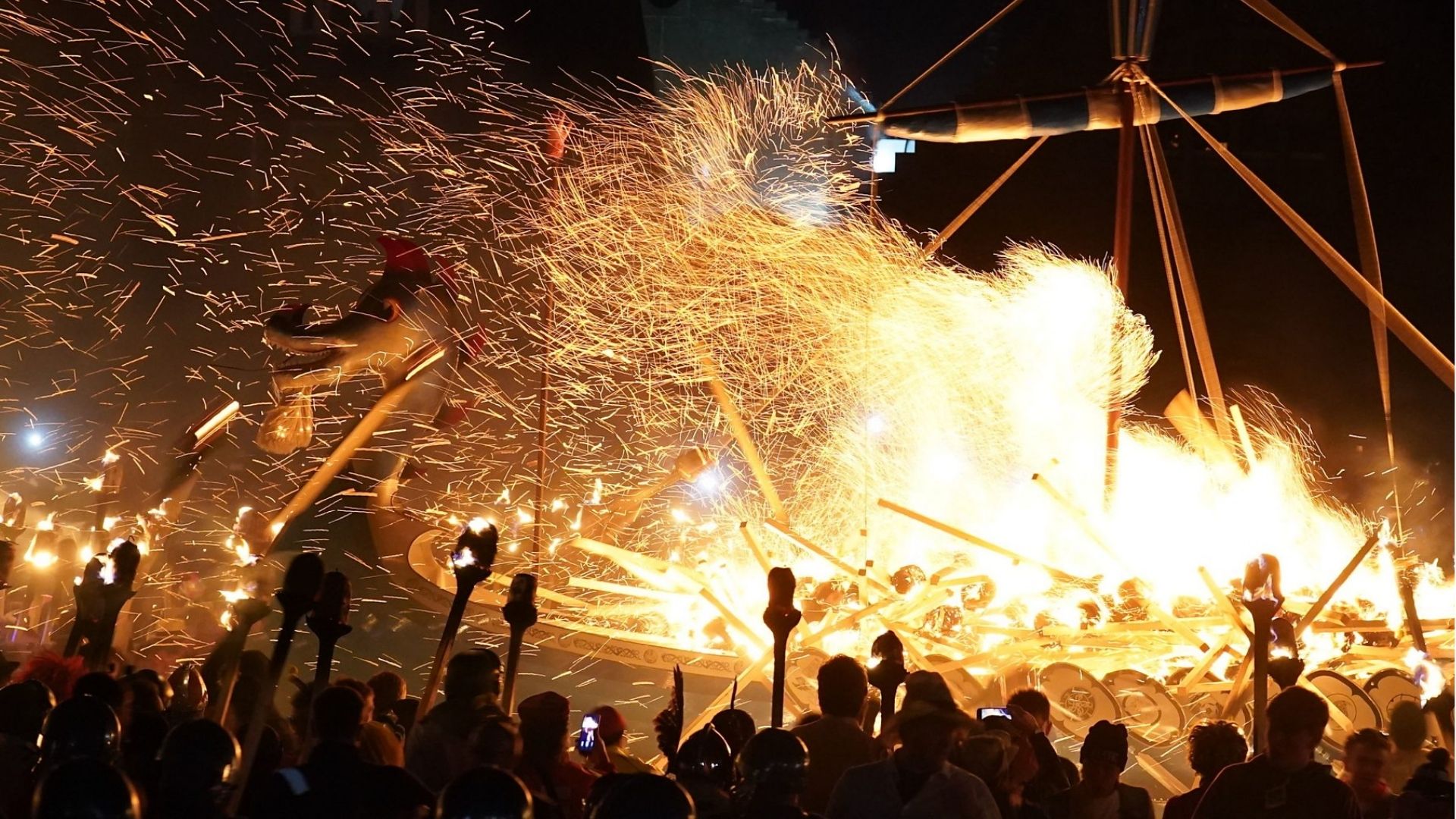 Viking galley burning surrounded by torches and sparks at Up Helly Aa