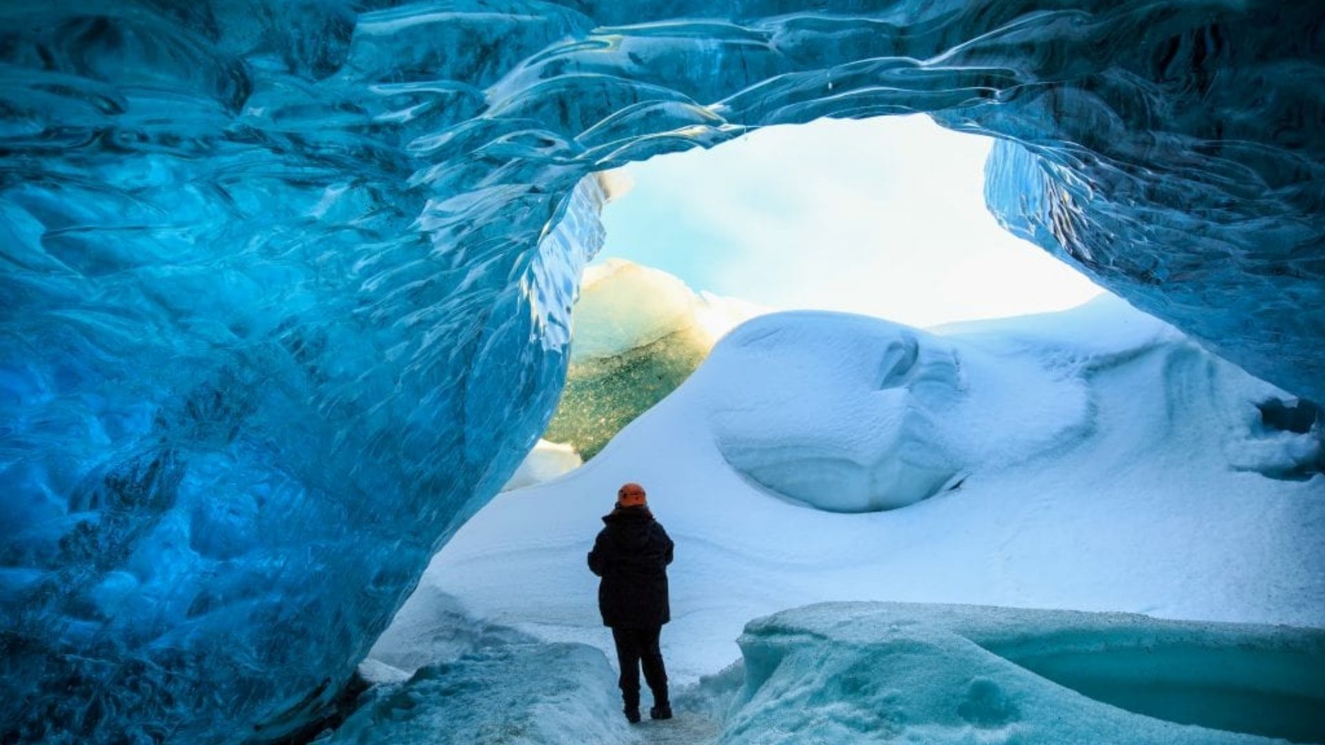 Traveler standing inside a blue ice cave in Iceland during winter, showcasing Europe’s February natural landscapes