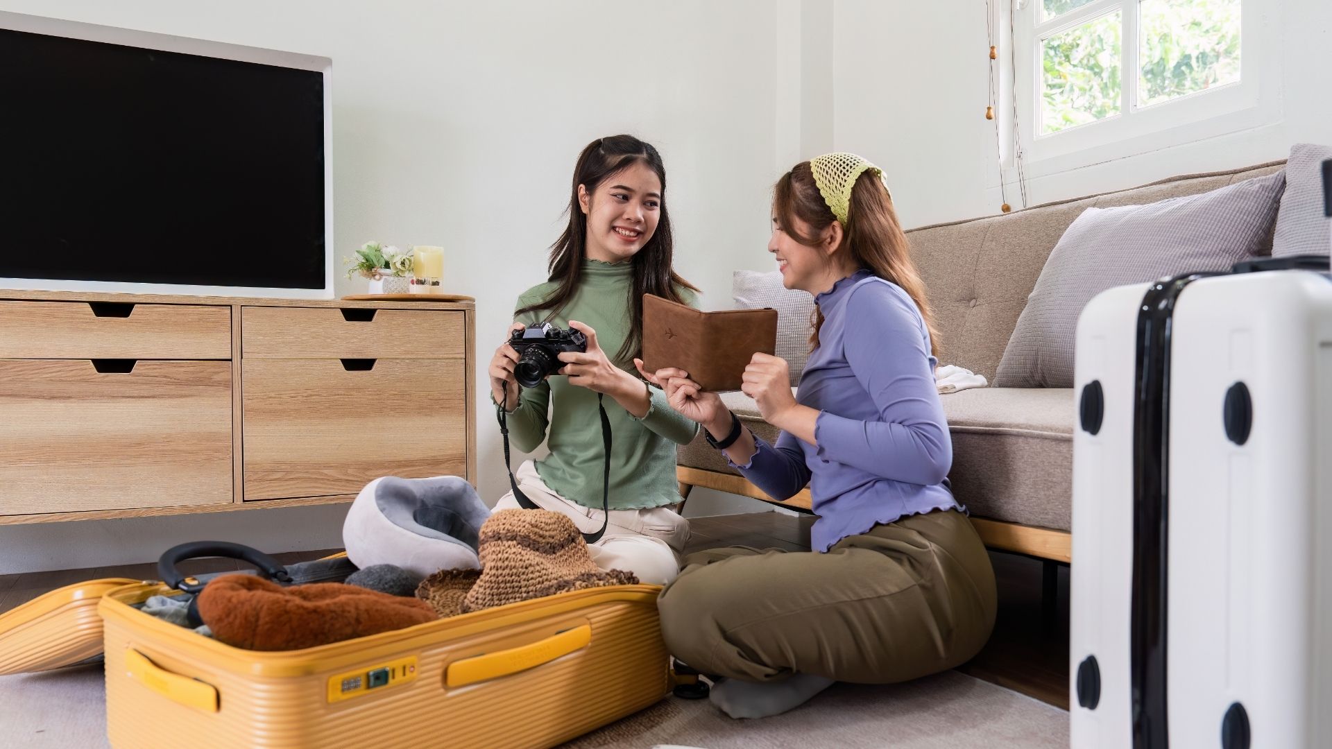 A woman and a friend are packing a suitcase for a trip
