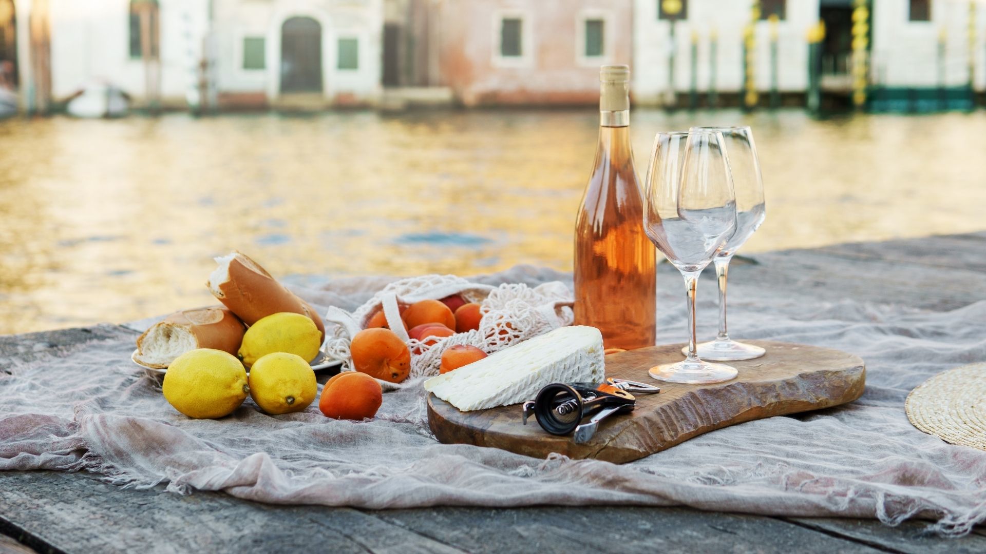 Rose wine, fruits and snacks on the wooden pier during picturesque picnic on the wooden dock
