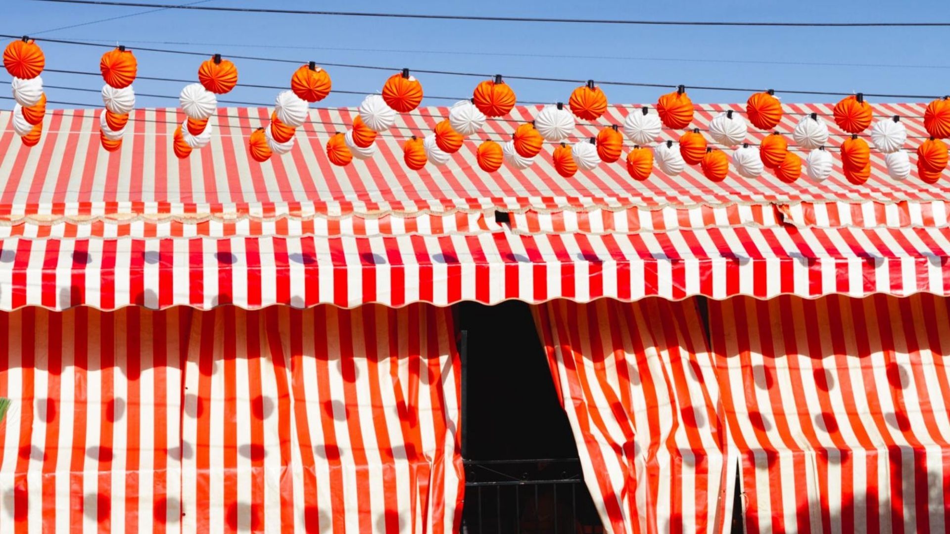 Red and white striped caseta tent decorated with lanterns at Feria de Abril in Seville
