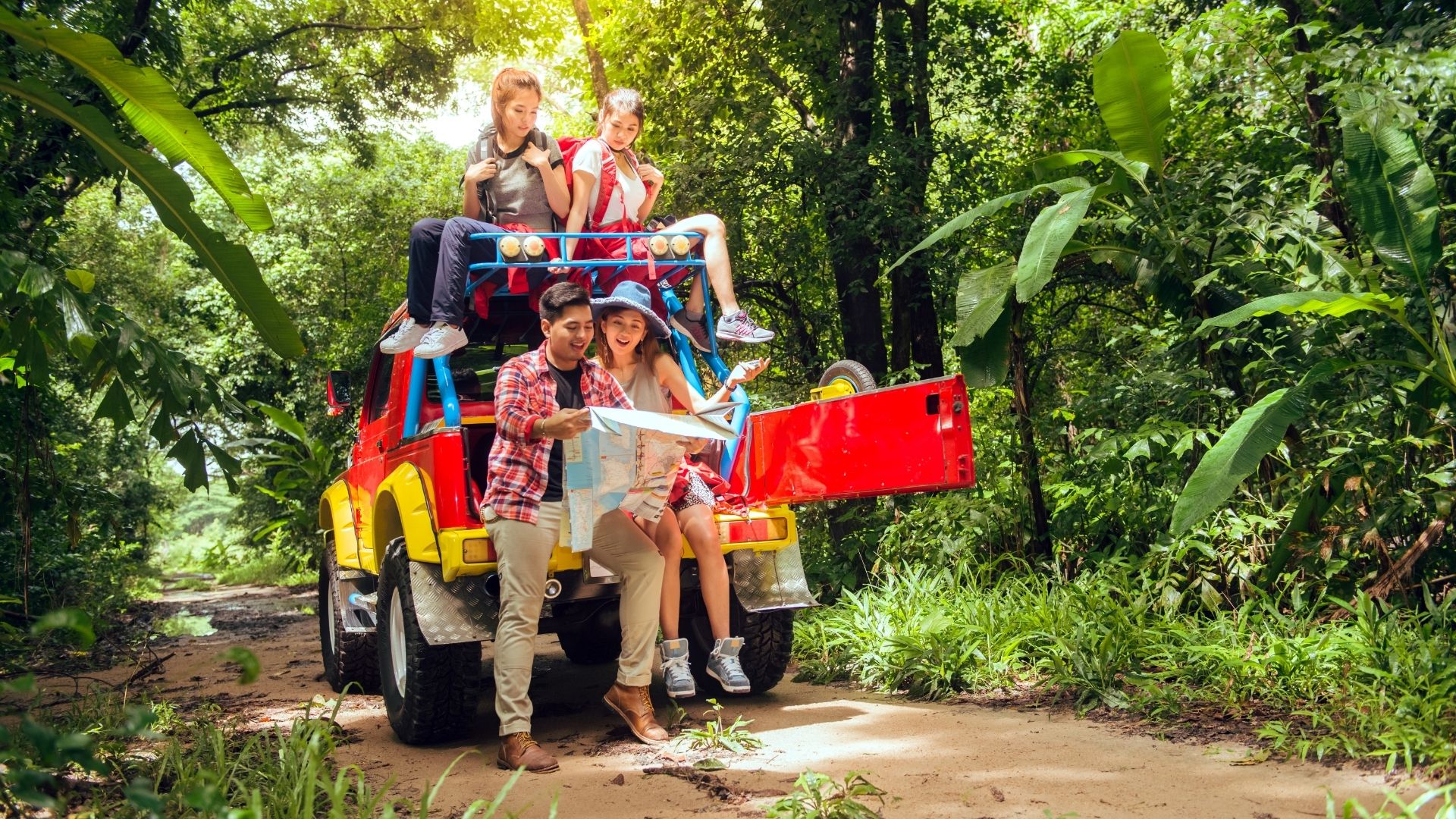 Happy asian young travellers with 4WD drive car off road in forest.
